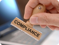 hand holding stamp reading 'COMPLIANCE'