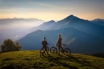 Two mountain bikers on bluff overlooking mountain range
