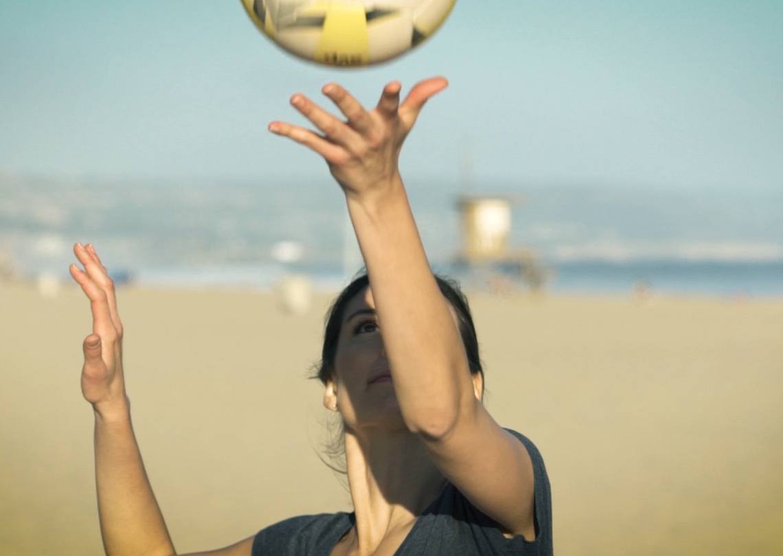 Someone serving a volleyball on the beach